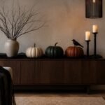 Aparador decorado para Halloween con calabazas en tonos neutros, ramas oscuras y luces sin llama